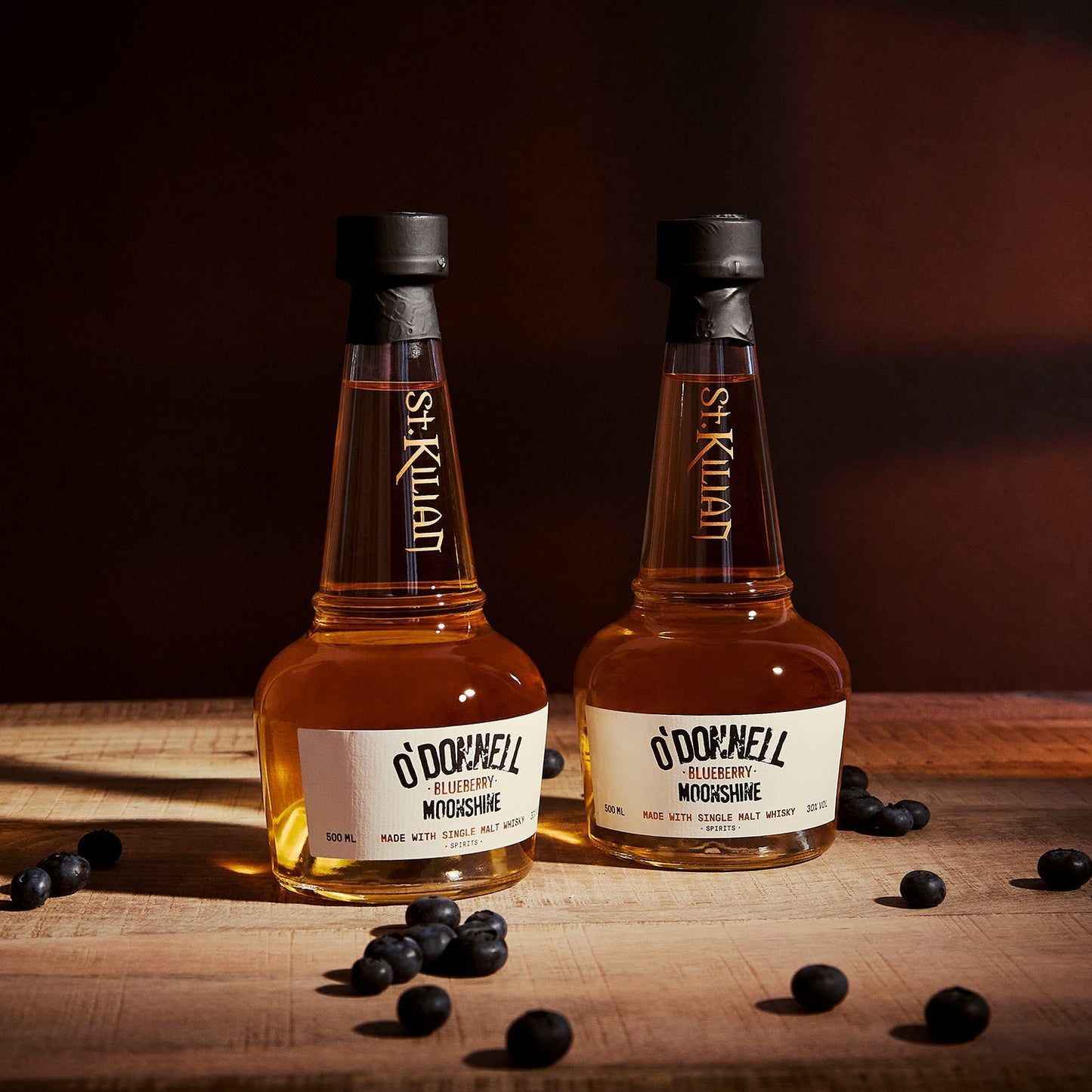 O'Donnell & St.Kilian Blueberry Moonshine Flasche umgeben von Blaubeeren beim Ausgießen
