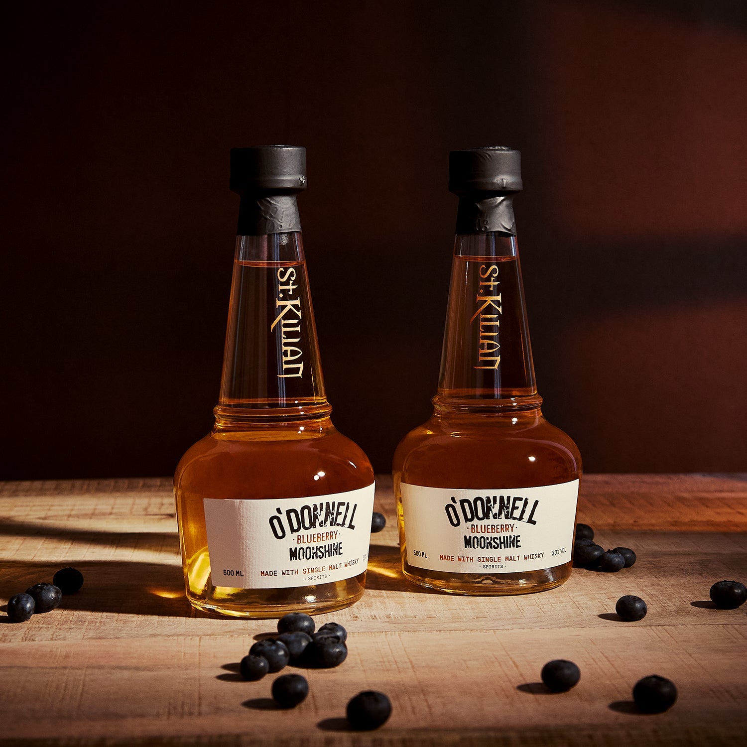 O'Donnell & St.Kilian Blueberry Moonshine Flasche umgeben von Blaubeeren beim Ausgießen