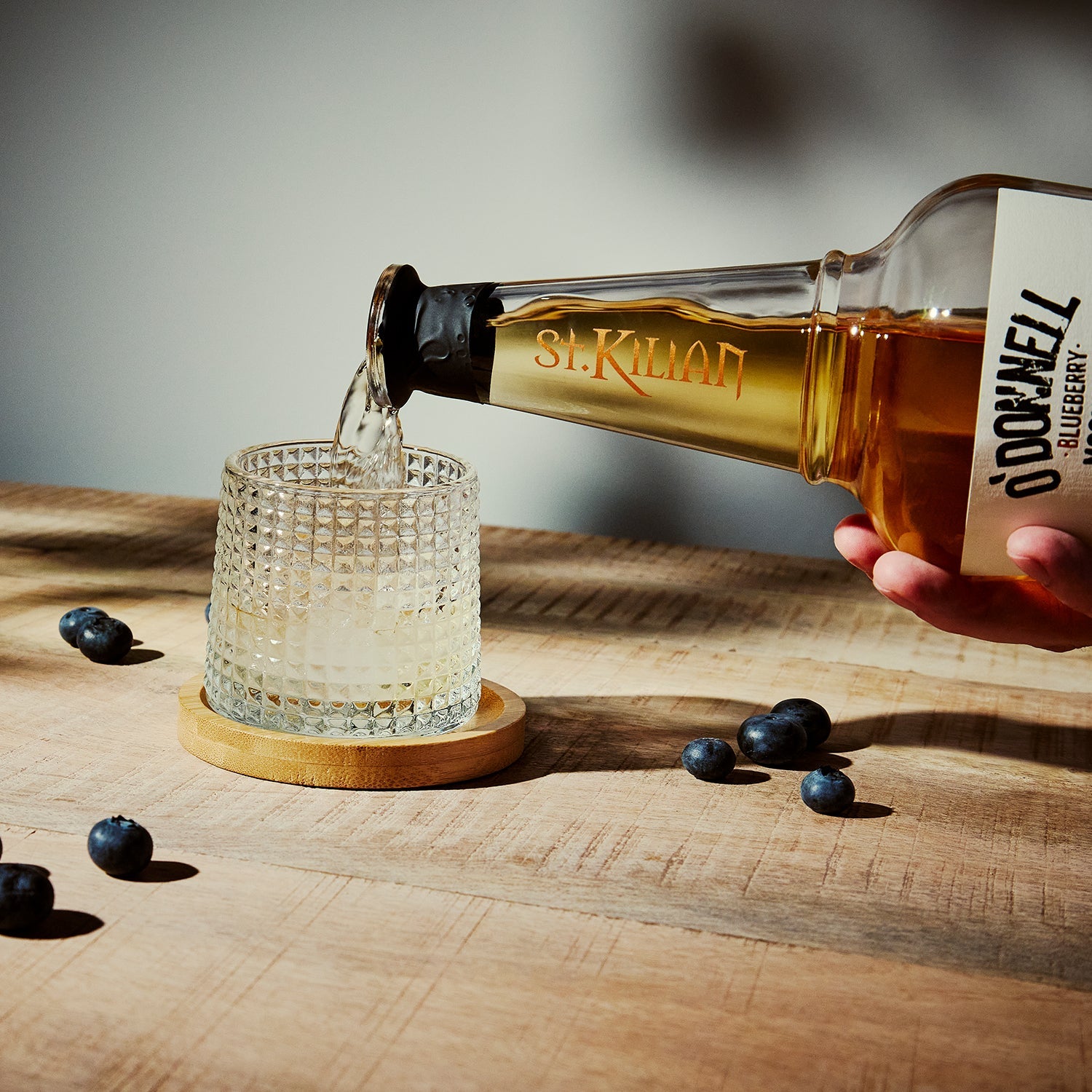O'Donnell & St.Kilian Blueberry Moonshine Flasche umgeben von Blaubeeren beim Ausgießen